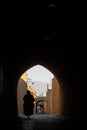 Silhouette of people riding a motorcycle in some narrow street made of clay walls and houses, typical from persian architecture
