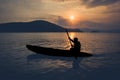 Silhouette of people rowing in kayaks