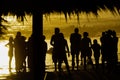 Silhouette of people standing on the beach at sunset behind a palapa Royalty Free Stock Photo