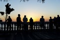 Silhouette of several people looking at Porto da Barra beach at dusk.