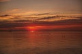 Silhouette of people on SUP boards on horizon of sea at orange sunrise. Active hobby on the water