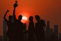 Silhouette of people in team of four celebrate trophy for winning of business competition with background of sunset behind Royalty Free Stock Photo