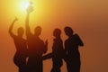 Silhouette of people in team of four celebrate trophy for winning of business competition with background of sunset Royalty Free Stock Photo
