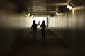 Silhouette of people in the tunnel. The girls walk through an underground tunnel