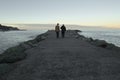 Silhouette of people walking on breakwater in sunset by atlantic ocean Royalty Free Stock Photo