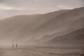 People walking in the far distance on the sandy beach at Brenton on Sea, photographed at sundown. Knysna, South Africa. Royalty Free Stock Photo