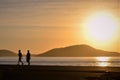 Silhouette of people walking on the shore of the beach at dawn