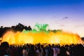 Silhouette of people watching at colorful illuminated musical fountains in the evening. Light and water night show performance. Royalty Free Stock Photo