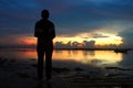 Silhouette of a person in the beach at sunrise. Young woman standing alone in solitude watching the burning sky light over sea Royalty Free Stock Photo