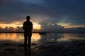 Silhouette of a person in the beach at sunrise. Young woman standing alone in solitude watching the morning sky light on sea. Royalty Free Stock Photo