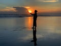 Silhouette of the person in the beach at sunset background. Woman standing alone with sun in hands. Royalty Free Stock Photo