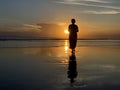 Silhouette of the person in the beach at sunset. A Woman walking alone toward the sun. Fragility concept. Royalty Free Stock Photo