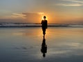 Silhouette of the person walking alone in the beach at sunset. Fragility and loneliness concept. Royalty Free Stock Photo
