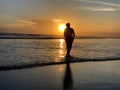 Silhouette of the person in the beach at sunset. Young woman walking alone with bare feet on the beach toward sun light. Self love Royalty Free Stock Photo