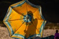 Silhouette of a person behind a beach summer umbrella. Beach sea concept. Colorful yellow summer shade umbrella Royalty Free Stock Photo