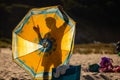 Silhouette of a person behind a beach summer umbrella. Beach sea concept. Colorful yellow summer shade umbrella Royalty Free Stock Photo