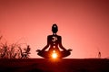 Silhouette of a person doing yoga with the root chakra symbol Royalty Free Stock Photo