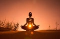 Silhouette of a person doing yoga with the root chakra symbol Royalty Free Stock Photo