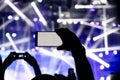 Silhouette of a person hand shooting the concert with his smart phone