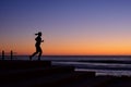 silhouette of person jogging on beach steps at dawn Royalty Free Stock Photo