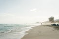 The silhouette of a person on an otherwise deserted beach. the wind blows the sand in streaks across the beach.