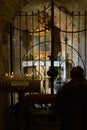 A silhouette of a person praying in a church in the shade against the background of a portrait of St. Peter