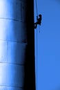 Silhouette of Person on Ropes Painting Sign on Side of Building Silo Royalty Free Stock Photo