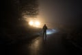 strange light in a dark forest at night. Silhouette of person standing in the dark forest with light. Horror halloween concept. Royalty Free Stock Photo