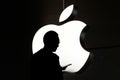 Silhouette of a person using mobile phone in front of the Apple logo