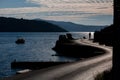 Silhouette of a person walking on beachfront asphalt road, silhouettes of cars on the left side of the road