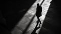 Silhouette of a person walking, cast in shadow and light on a tiled floor Royalty Free Stock Photo