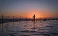 One swimmer along the edge of a pool at sunrise