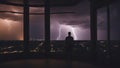 silhouette of a person in the window watching the lightning and thunderstorm flash with raining background from his window, Royalty Free Stock Photo