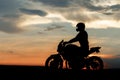 Silhouette photo of biker driving motorcycle in sunset on the on country road. Royalty Free Stock Photo