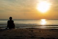 The silhouette photo of a man sitting alone on the beach enjoy sunrise moment