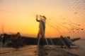 Silhouette photo. The old fisherman casting the net in the sunset. Royalty Free Stock Photo