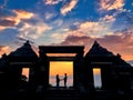 Silhouette photo of a pair of lovers standing holding hands at the gate of the temple