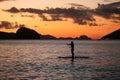 A silhouette photo of a young girl on a standing paddle. Active holidays, life on the beach. Philippines