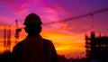 Silhouette photograph of a technician facing away from the camera on an active construction site in sunset Royalty Free Stock Photo