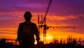 Silhouette photograph of a technician facing away from the camera on an active construction site in sunset Royalty Free Stock Photo