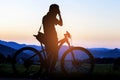 Silhouette of photographer in action take photo with bike on mountain with sunrise. Royalty Free Stock Photo