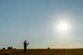 The silhouette of a photographer with a camera and a tripod in his hands in front of the sun. A photographer takes pictures of a Royalty Free Stock Photo