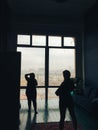 Silhouette of the photographer and model in the studio on the background of huge windows Royalty Free Stock Photo