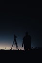 Silhouette of a photographer in Okinawa, Japan, capturing the night sky with a camera on a tripod Royalty Free Stock Photo