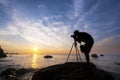Silhouette a photographer taking pictures of sunrise on a rock, Royalty Free Stock Photo