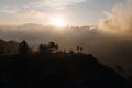 silhouette of a photographer with a tripod standing on a rock at dawn