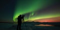 silhouette of photographer with a tripod who takes a photo of Aurora lights in the night sky Royalty Free Stock Photo