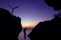 Silhouette of photographer using the camera to capture the sunset in a cave by the sea at twilight sky sunset