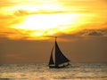 SILHOUETTE: Local Filipino person sails along a calm ocean at golden sunset. Royalty Free Stock Photo