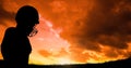 Silhouette player wearing sport helmet against cloudy sky during sunset